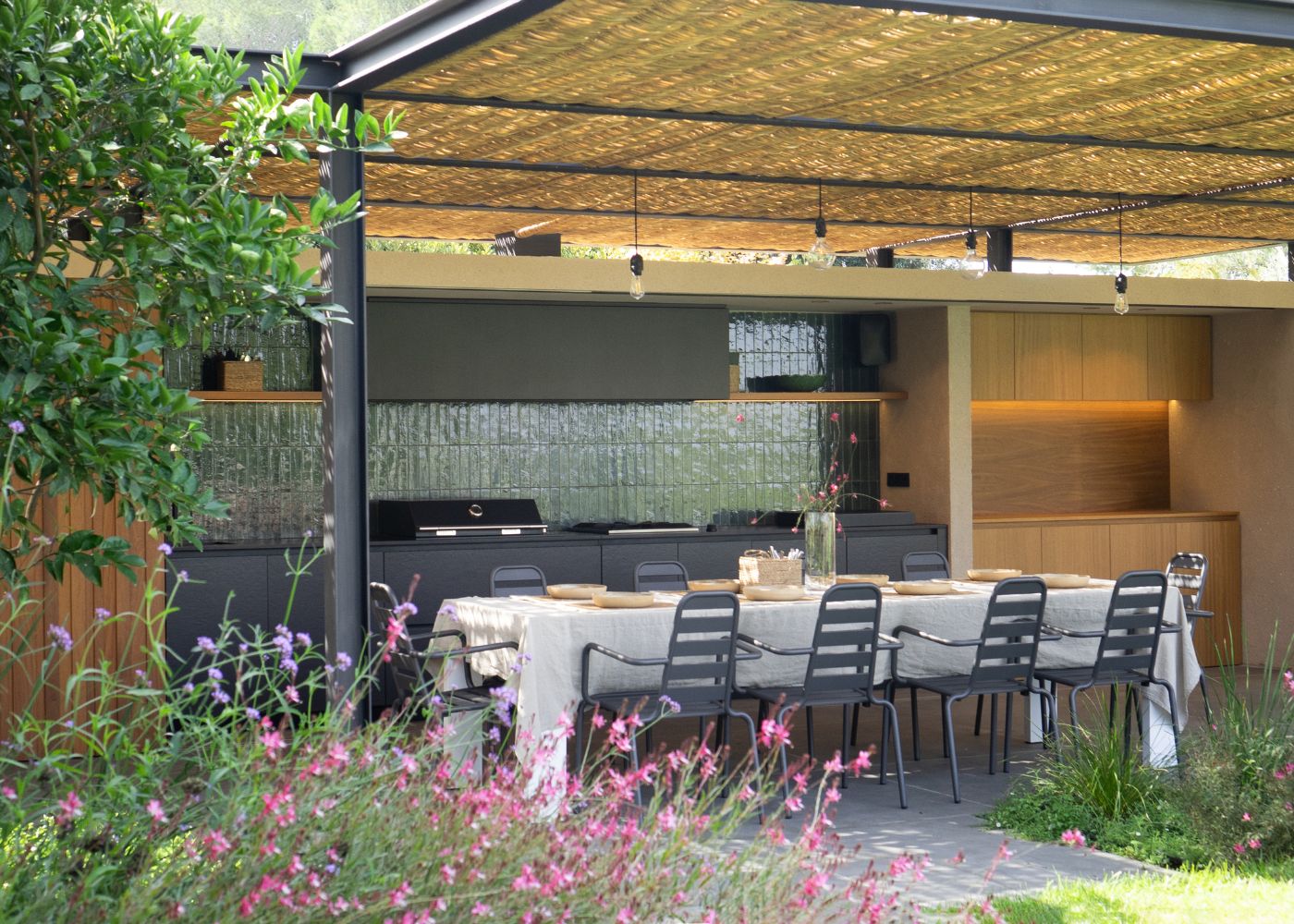 Cuisine extérieure sous pergola intégrée dans un environnement naturel et végétalisé